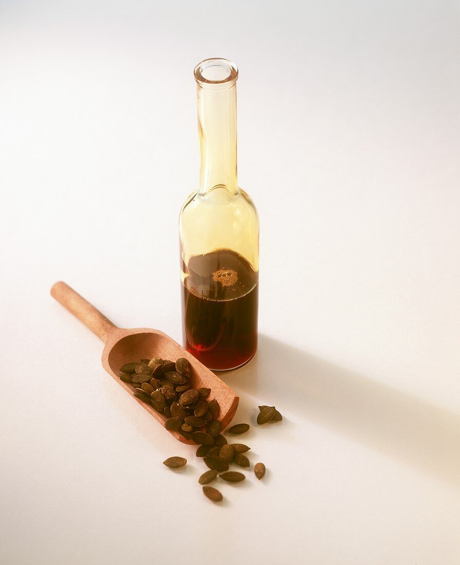 Kürbiskernöl in Flasche und Kürbiskerne auf Holzschaufel