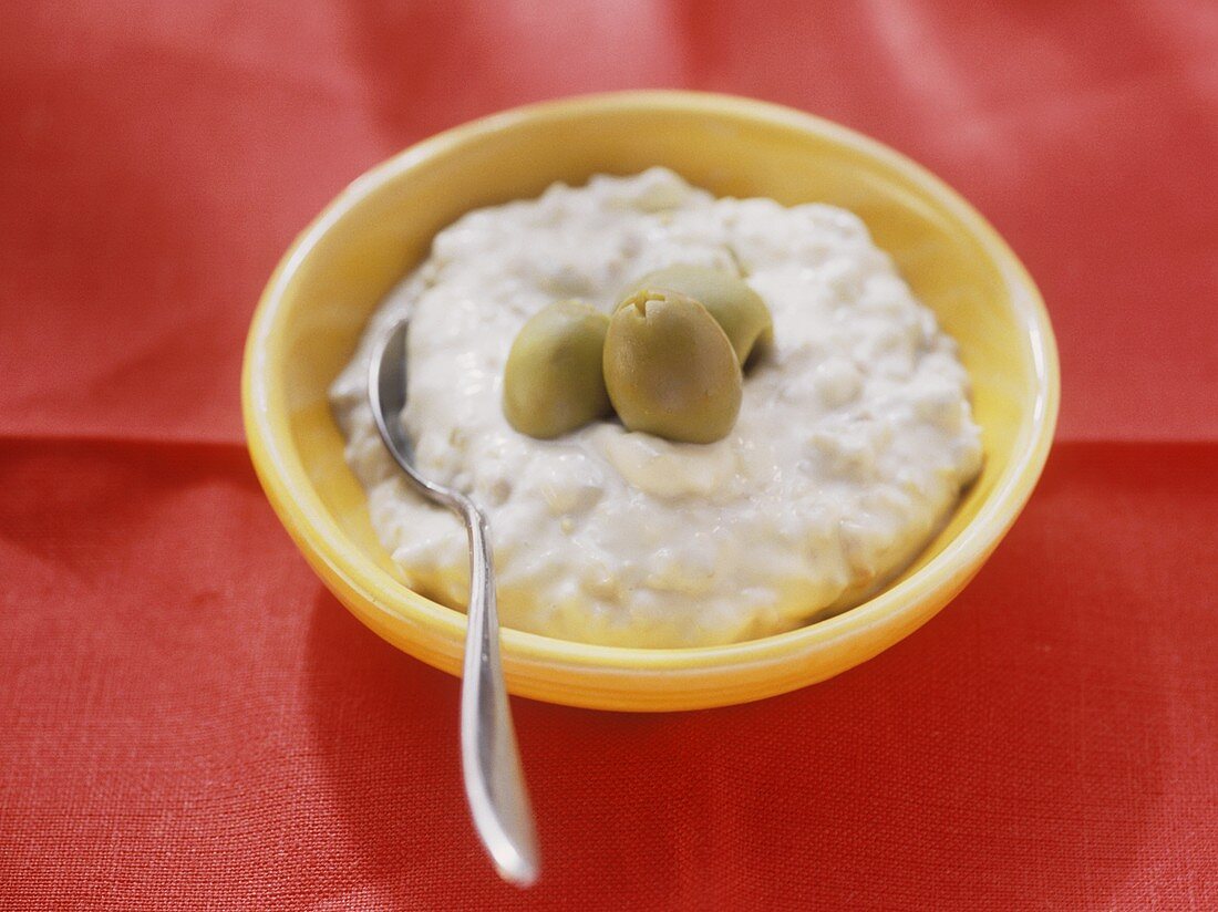 Oliven-Mayonnaise mit drei grünen Oliven im Schälchen