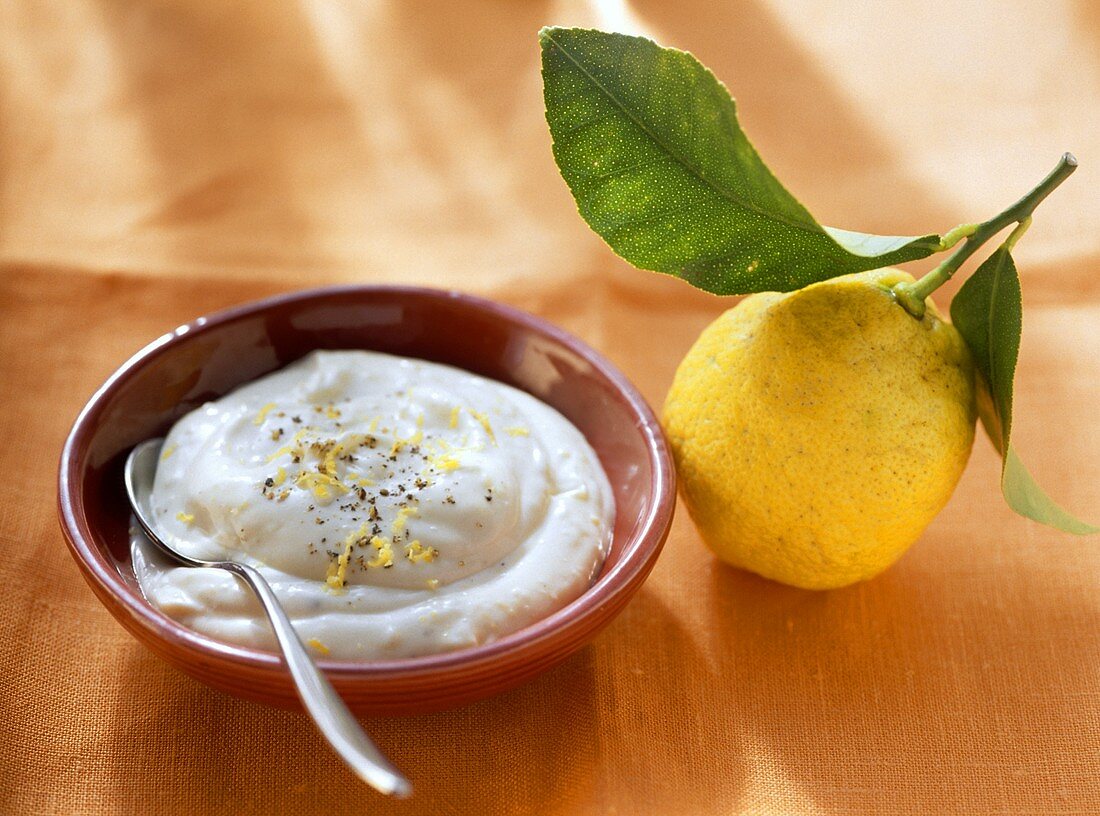 Lemon mayonnaise in bowl, a lemon beside it