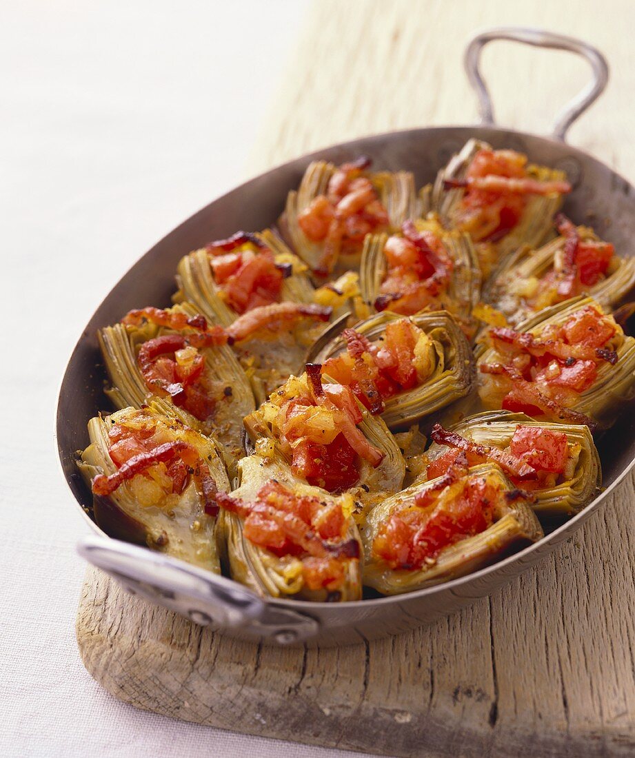 Stuffed artichokes with tomatoes and bacon in pan