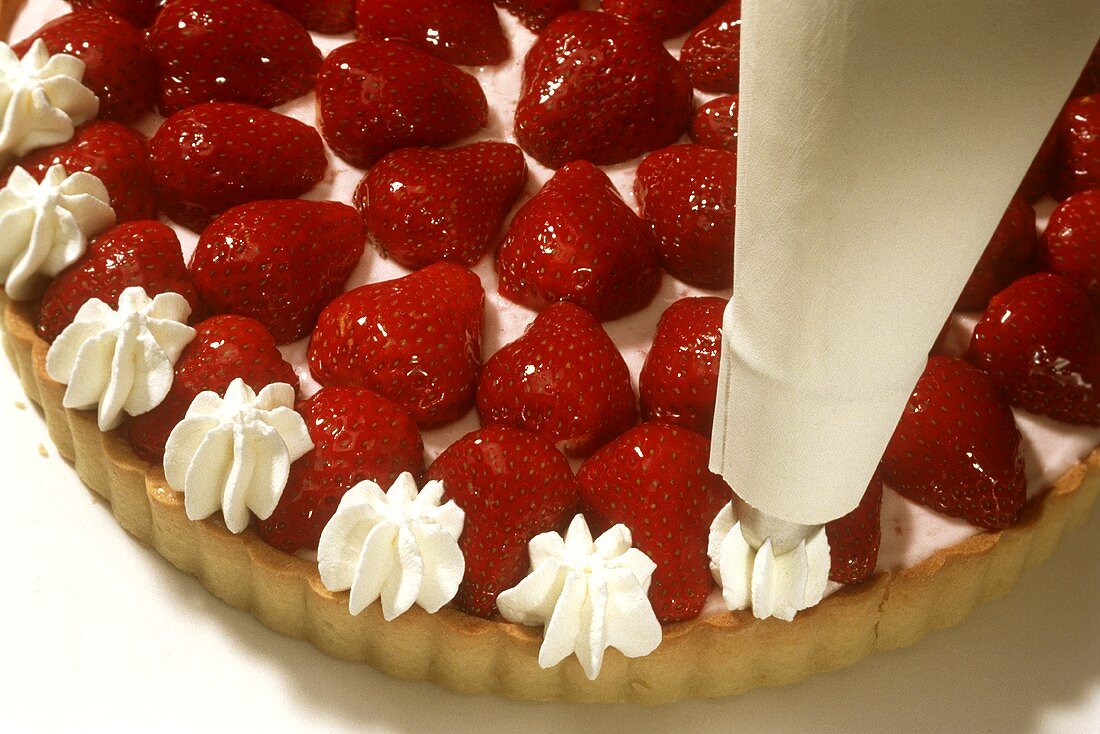 Piping cream rosettes on to a strawberry flan