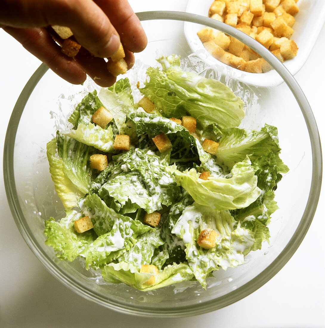 Scattering croutons on Caesar salad