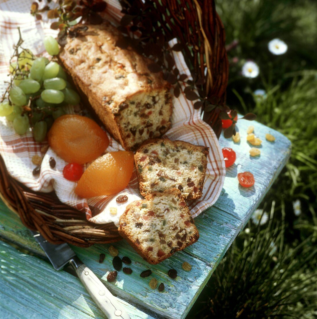Cake with crystallised fruit in a basket on grass