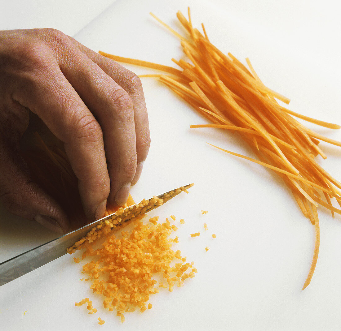 Finely chopping strips of carrot