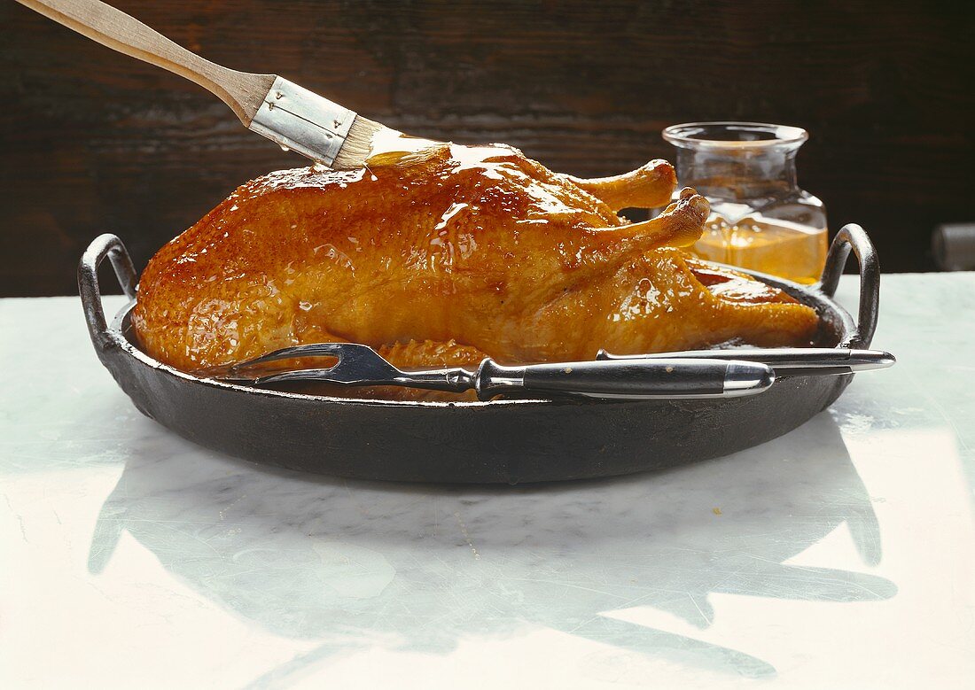 Brushing roast duck with orange glaze