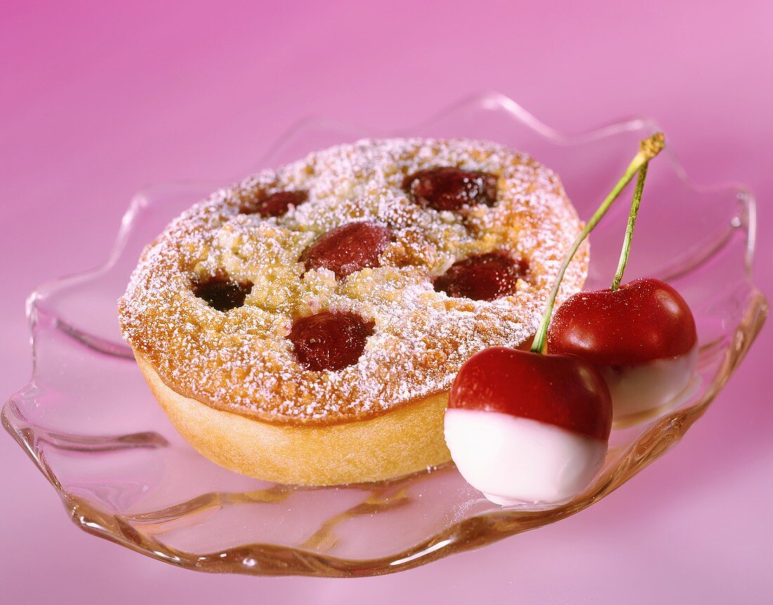 Small cherry cake with icing sugar on glass plate