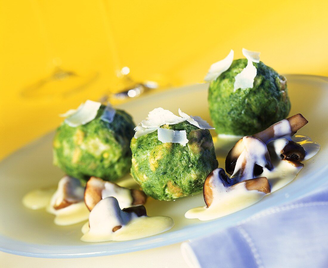 Spinach dumplings on mushrooms with cream sauce and parmesan