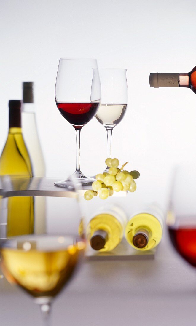 Red and white wine glasses, wine bottles & green grapes