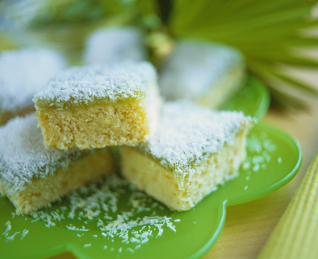 Coconut cake, cut into pieces, on green plate