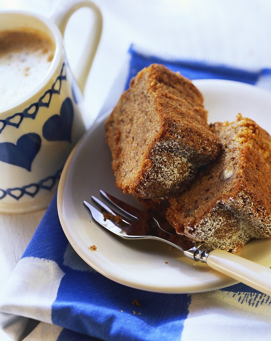 Two pieces of spiced nut ring on plate beside coffee cup