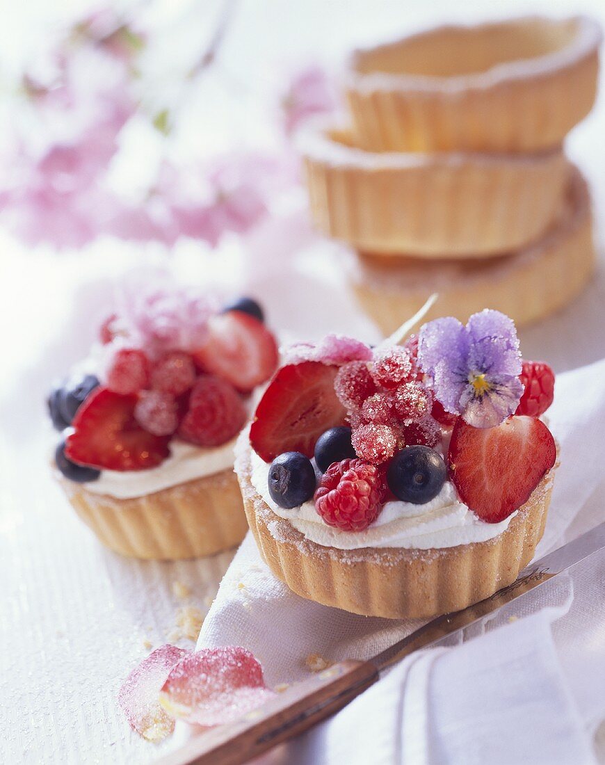 Berry tart with cream and sugared edible flowers