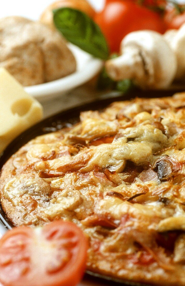 Pizza mit Champignons und Tomaten in Backform