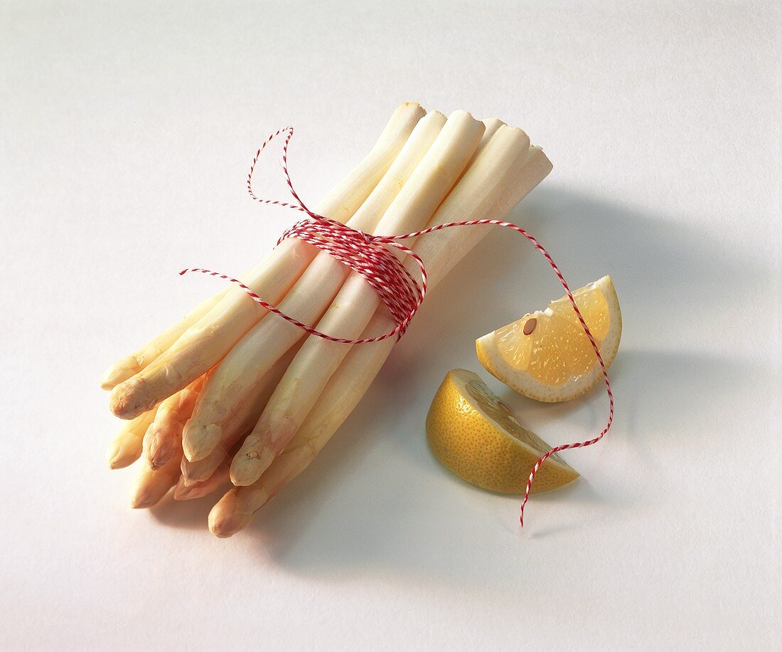 A bundle of white asparagus and lemon wedge