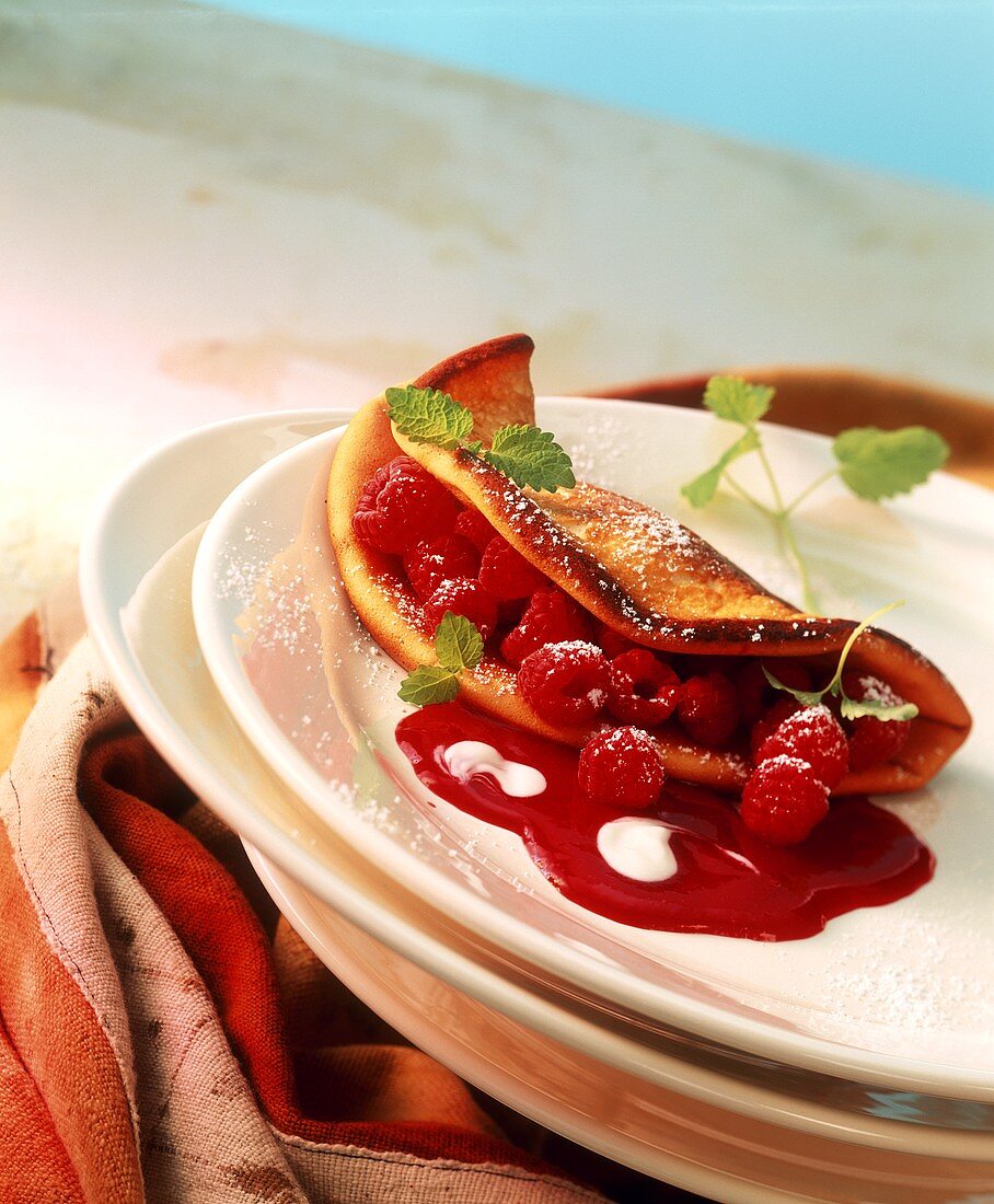 Raspberry omelette with icing sugar and mint leaves