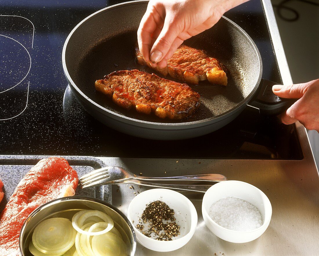 Seasoning fried steaks with salt and pepper