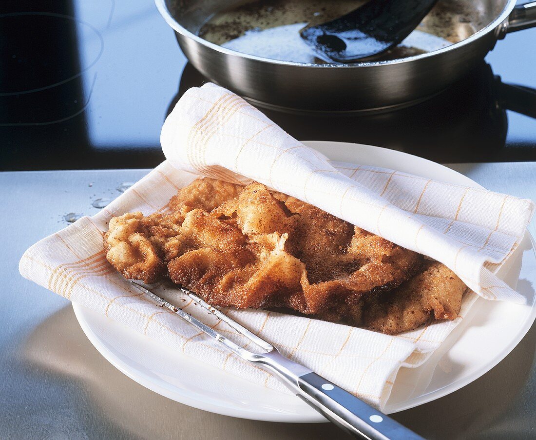 Draining breaded veal escalope and keeping it warm