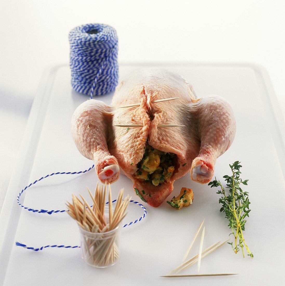 Stuffing chicken and securing with wooden cocktail sticks