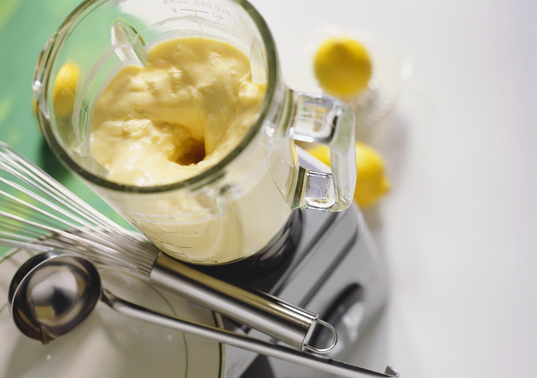 Mayonnaise im Mixer; Schneebesen, Kelle und Zitronen