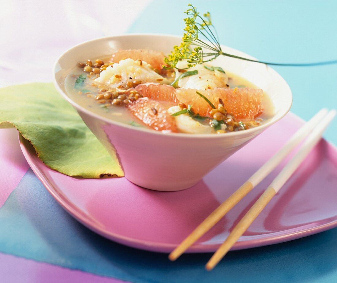 Linsen-Fisch-Topf mit Orangen in rosa Schale