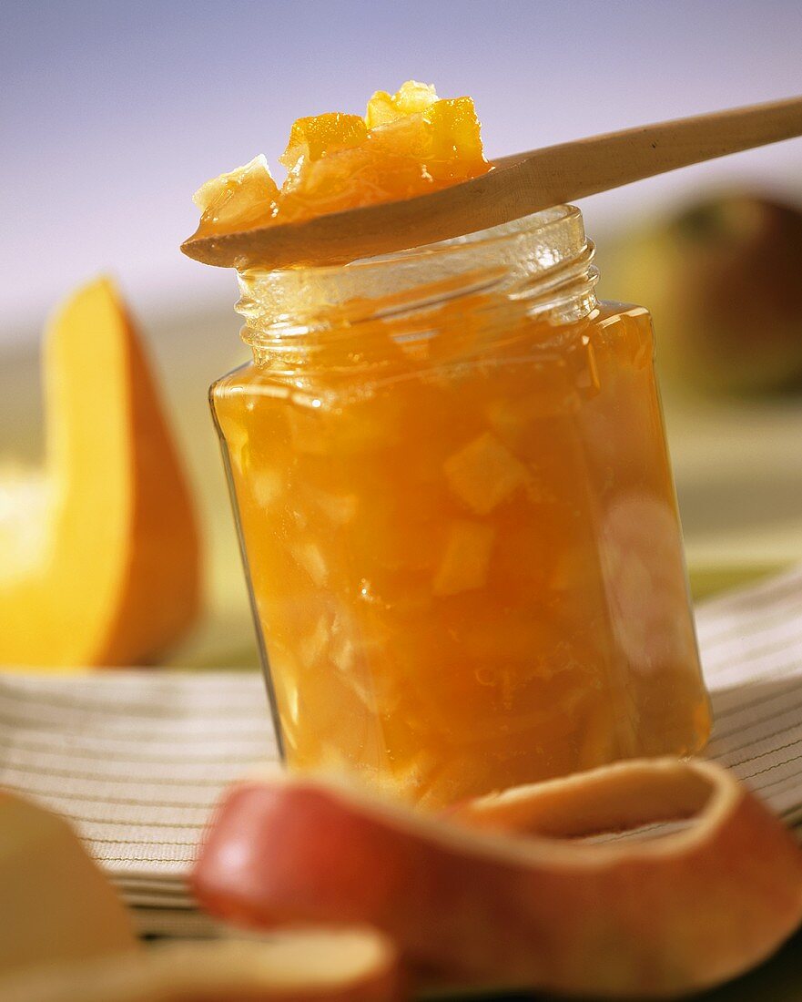 Apple and pumpkin preserve in jar and on wooden spoon