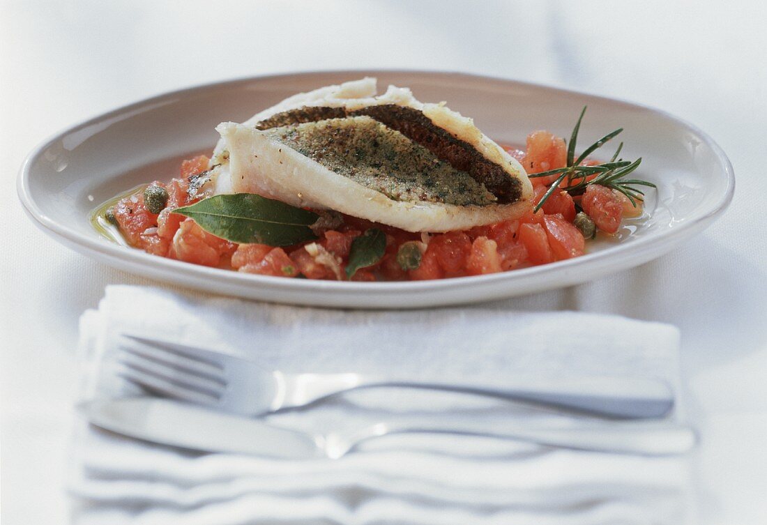 Provencal trout with tomato ragout on plate; cutlery