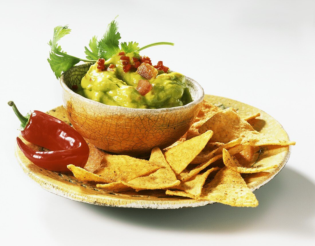 Guacamole with chili pepper and taco chips (from Mexico)