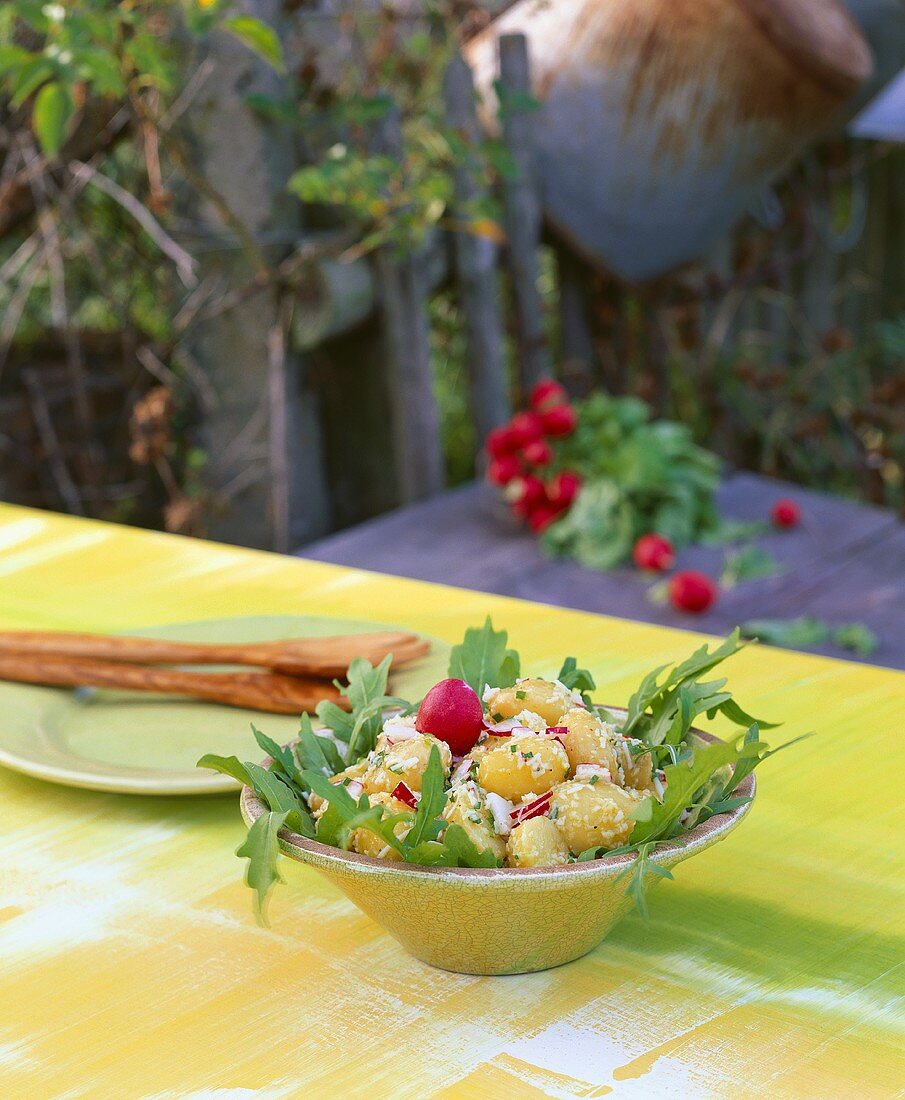 Kartoffel-Radieschen-Salat mit Rucola auf Tisch im Freien