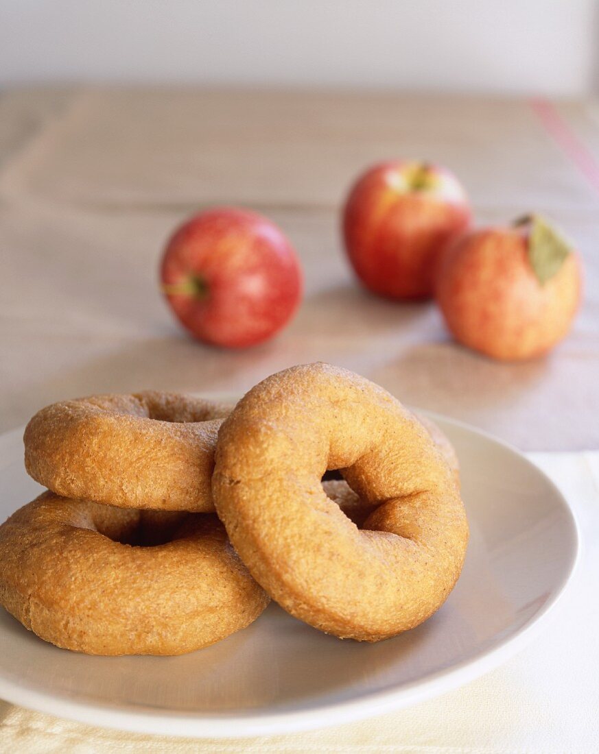 Apple doughnuts on plate in front of fresh apples