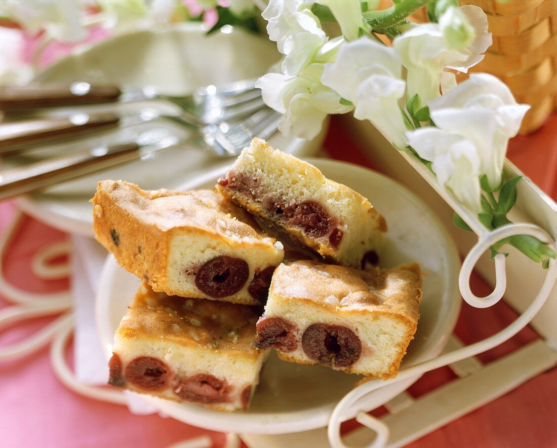Pieces of cherry cake on white plate; white flowers