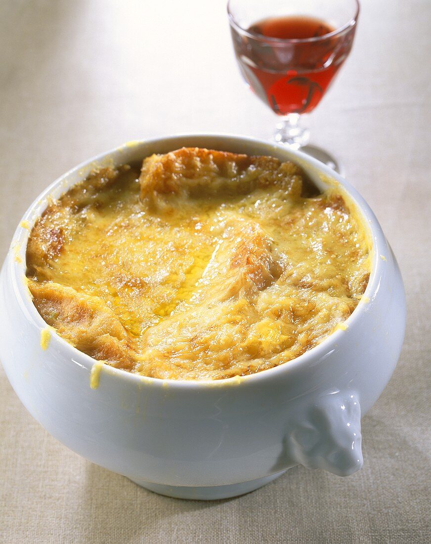 Onion soup in soup tureen; red wine glass