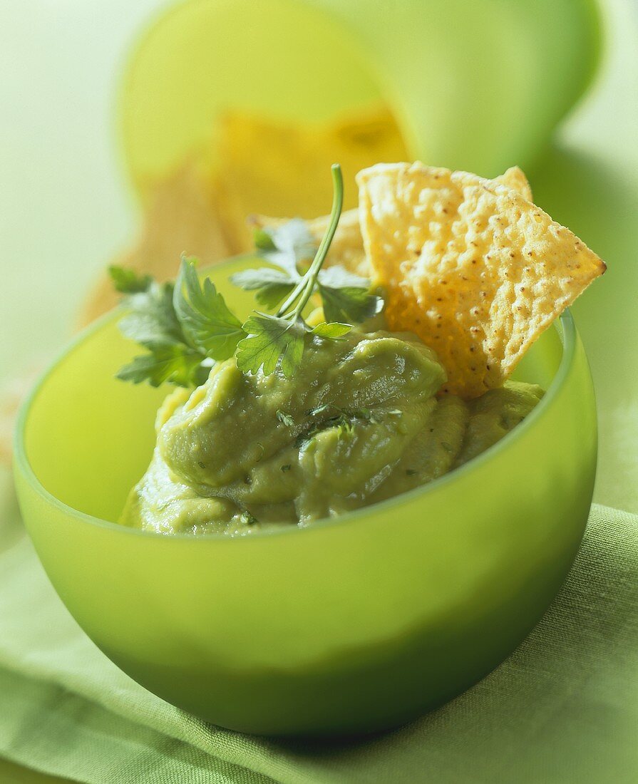 Avocado mousse with nachos (taco chips) in green bowl