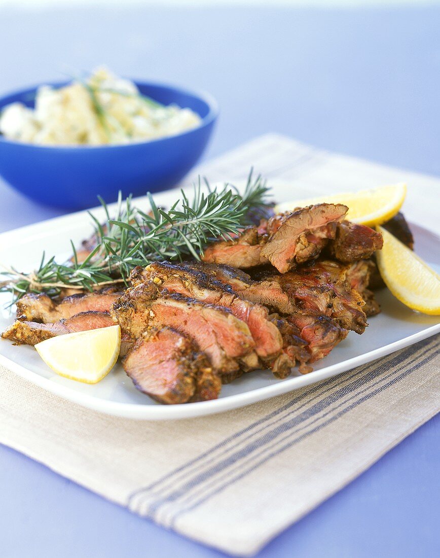 Lamb with rosemary and lemon wedges