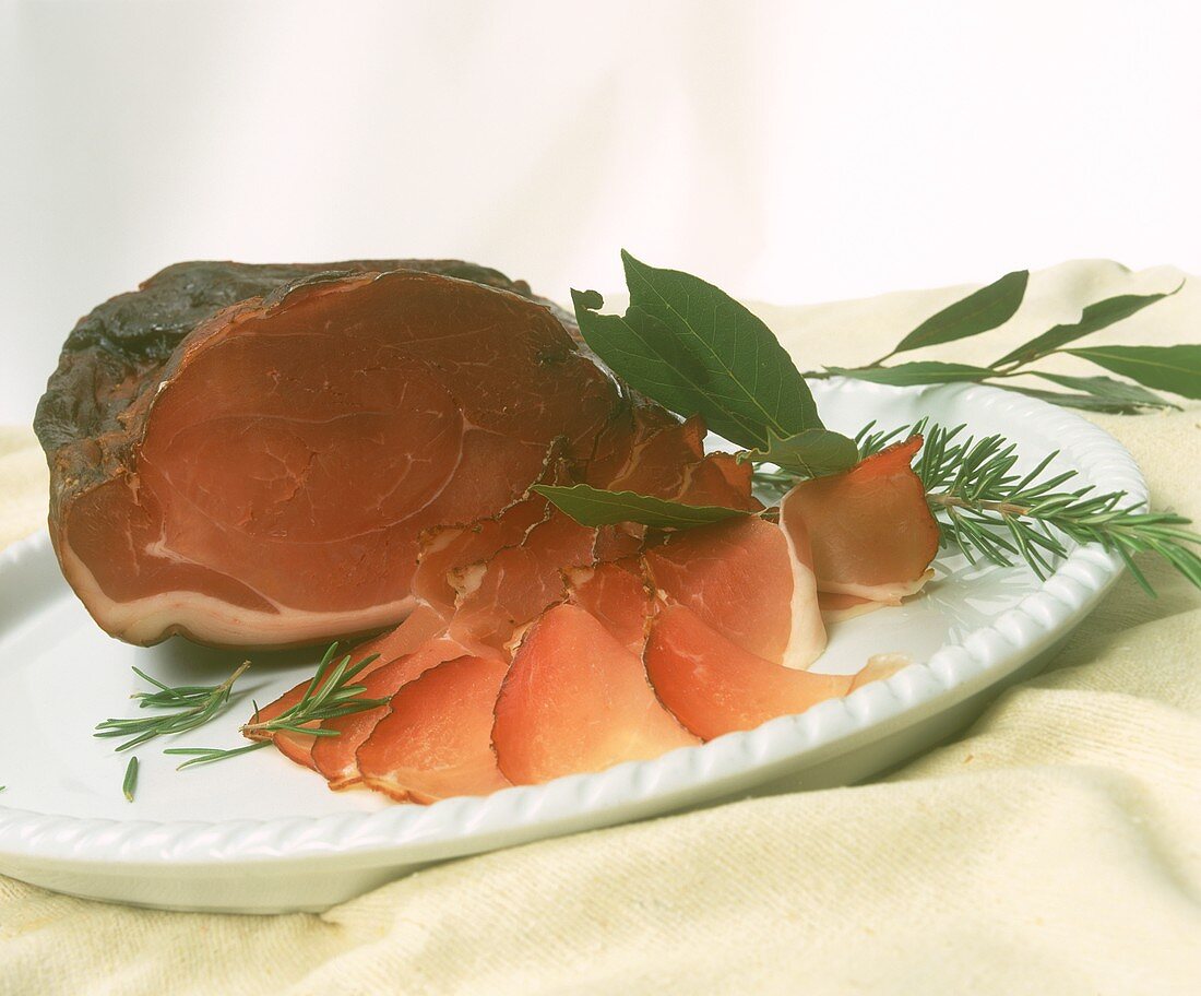 Raw ham garnished with rosemary and bay leaf