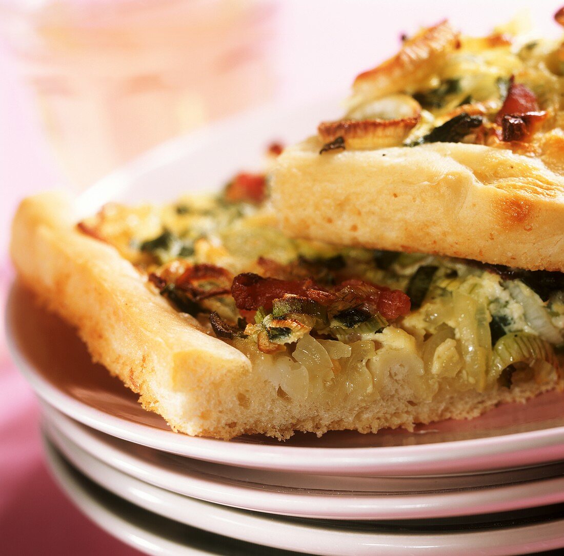 Spring onion tart with bacon on pile of plates