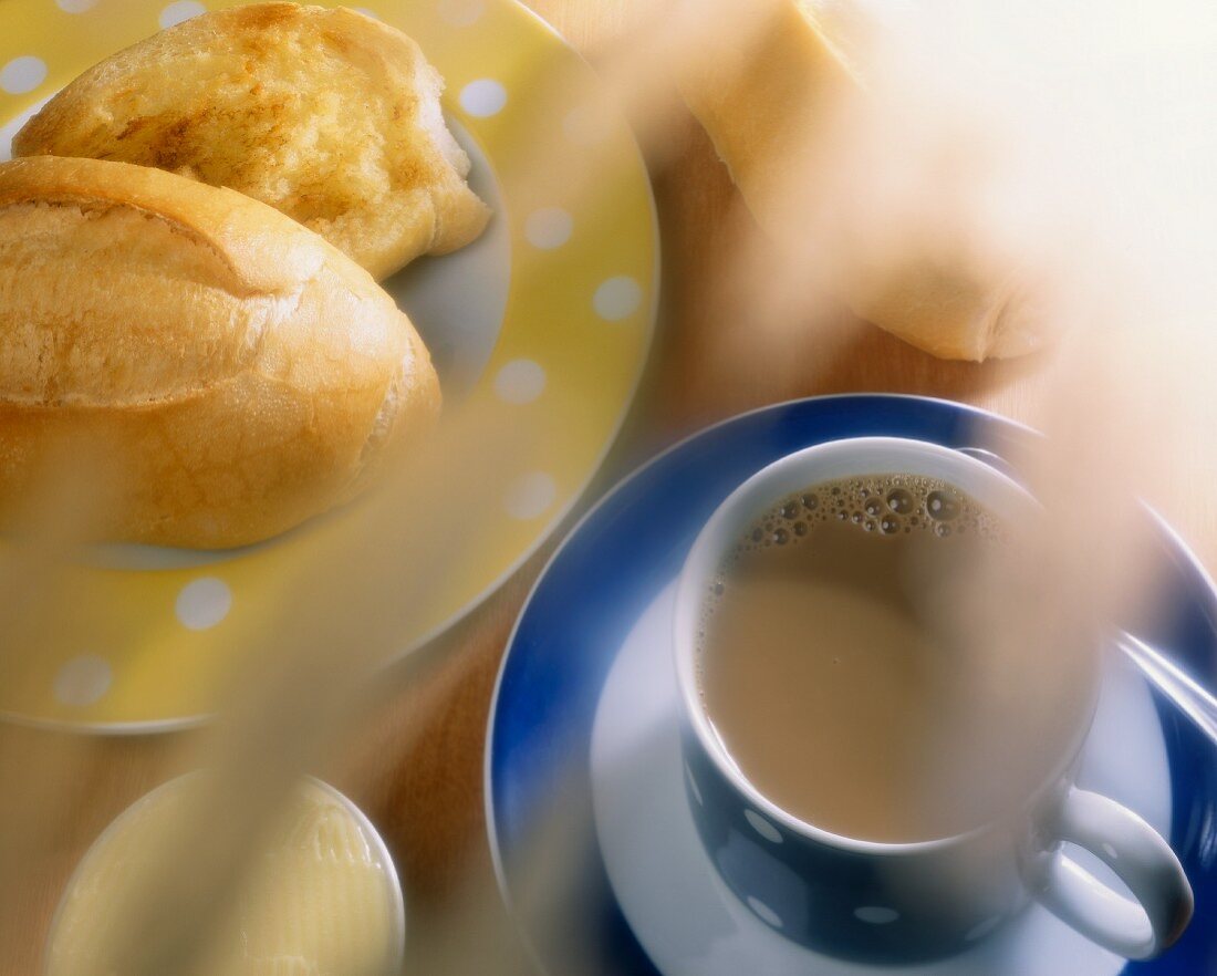 Brasilianisches Frühstück mit Milchkaffee, Brötchen, Butter