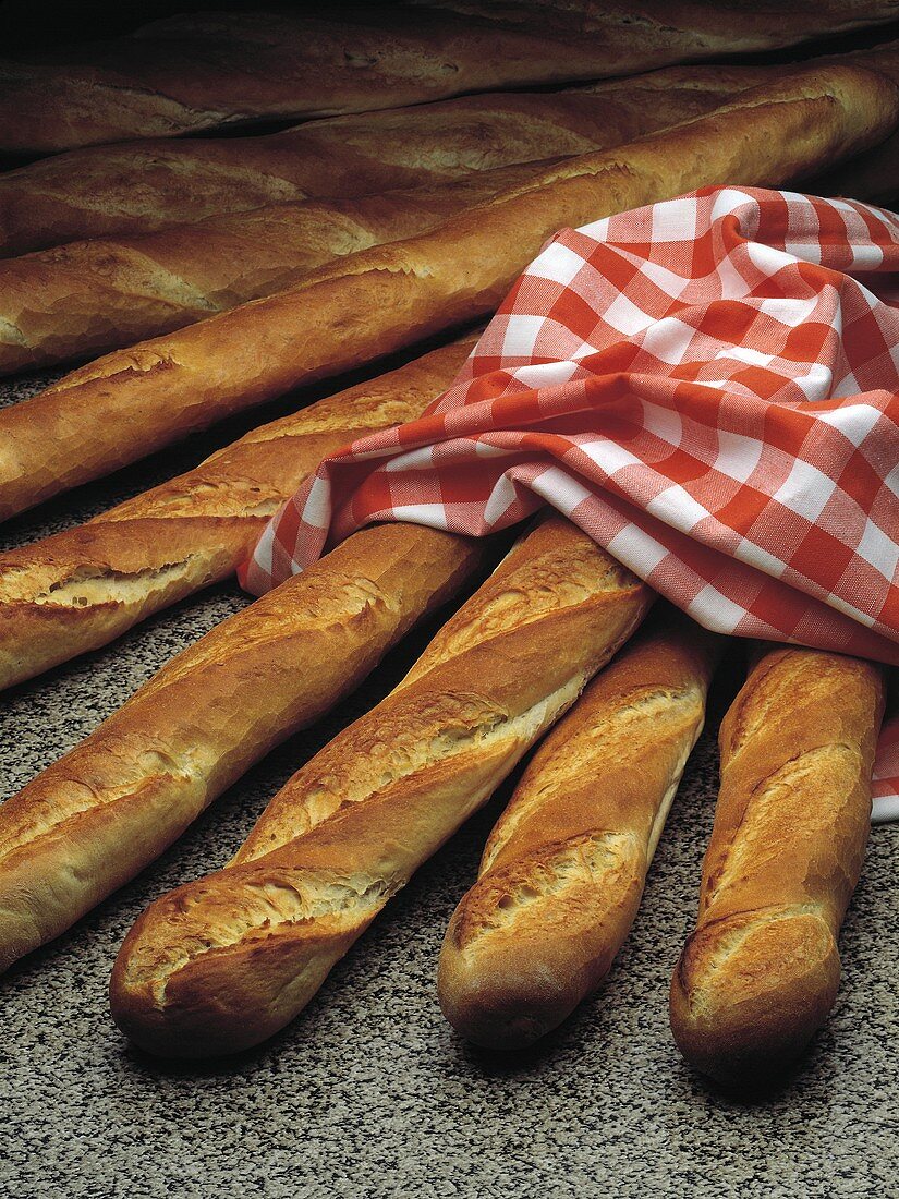 Several baguettes, partly covered with checked cloth