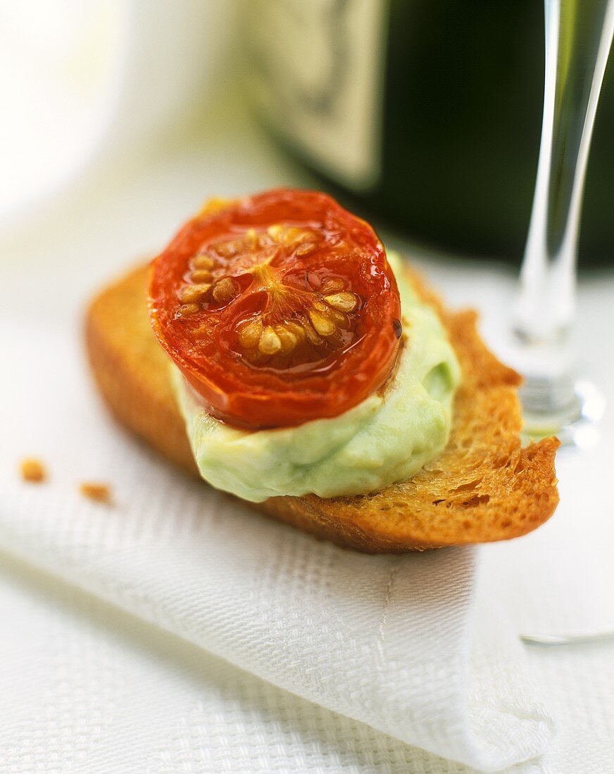 Crostini with avocado mousse and cherry tomato on napkin