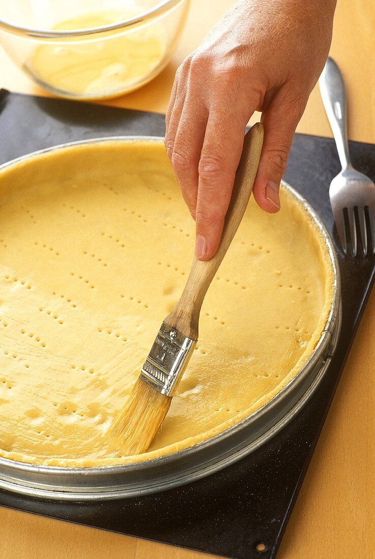 Brushing pastry base with egg yolk