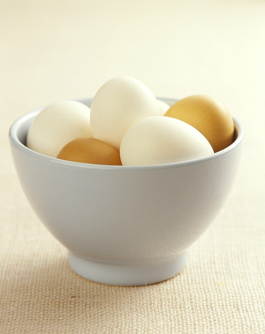 White and brown eggs in white bowl