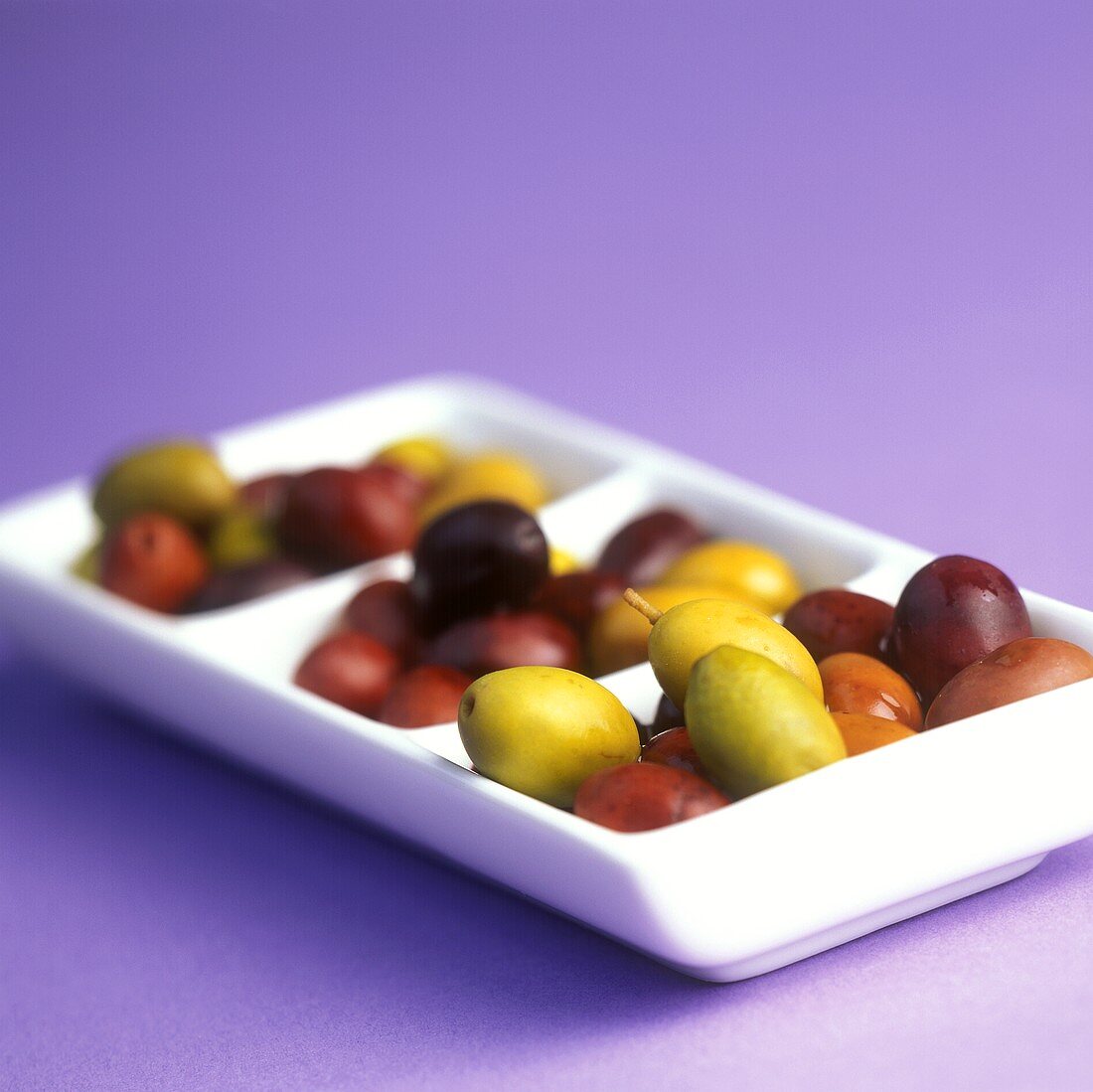 Green and black olives in white bowl