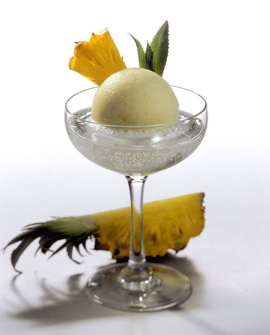 Pineapple ice cream in champagne glass by pineapple wedge