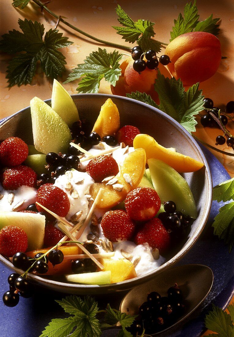 Fruit salad with cream, sunflower seeds and lemon grass