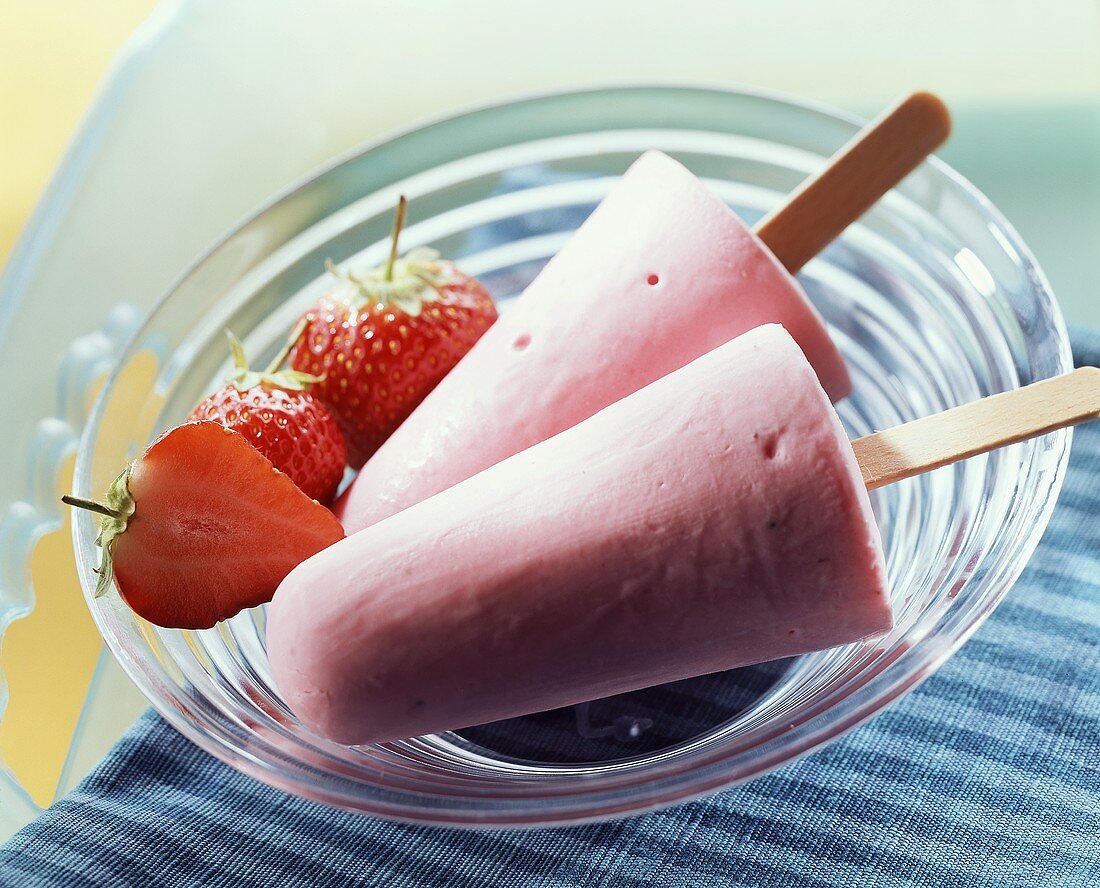 Erdbeer-Kefir-Stieleis und frische Erdbeeren in Glasschale