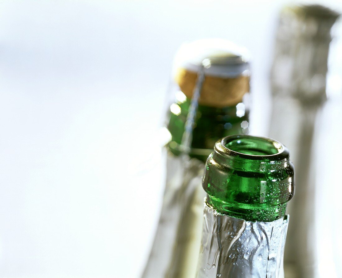 Three champagne bottles, one opened