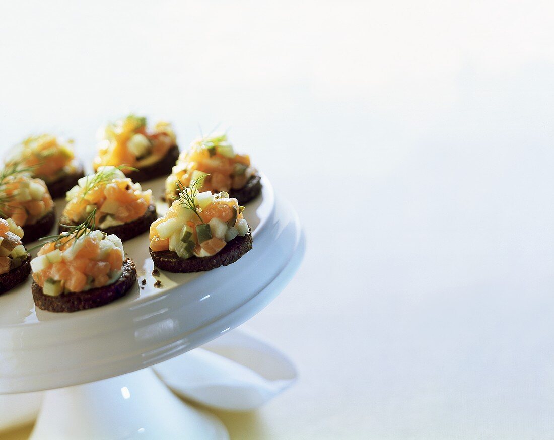 Pumpernickel rounds with salmon tartare on white platter