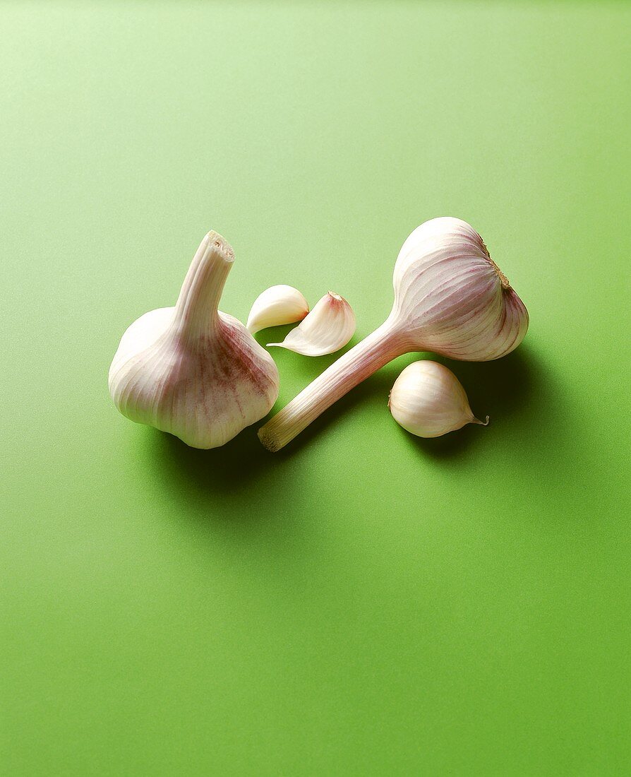 Garlic and cloves of garlic on green background