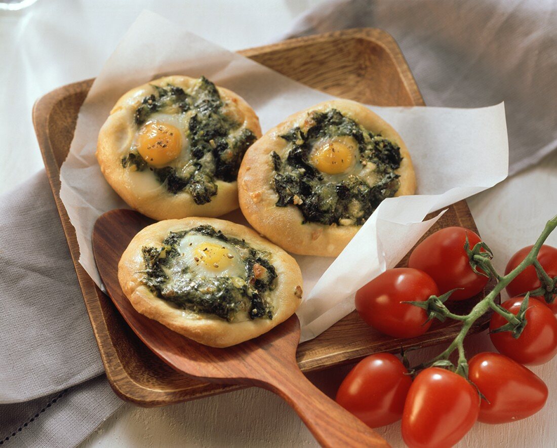 Small spinach pizzas with egg;  tomatoes on the vine