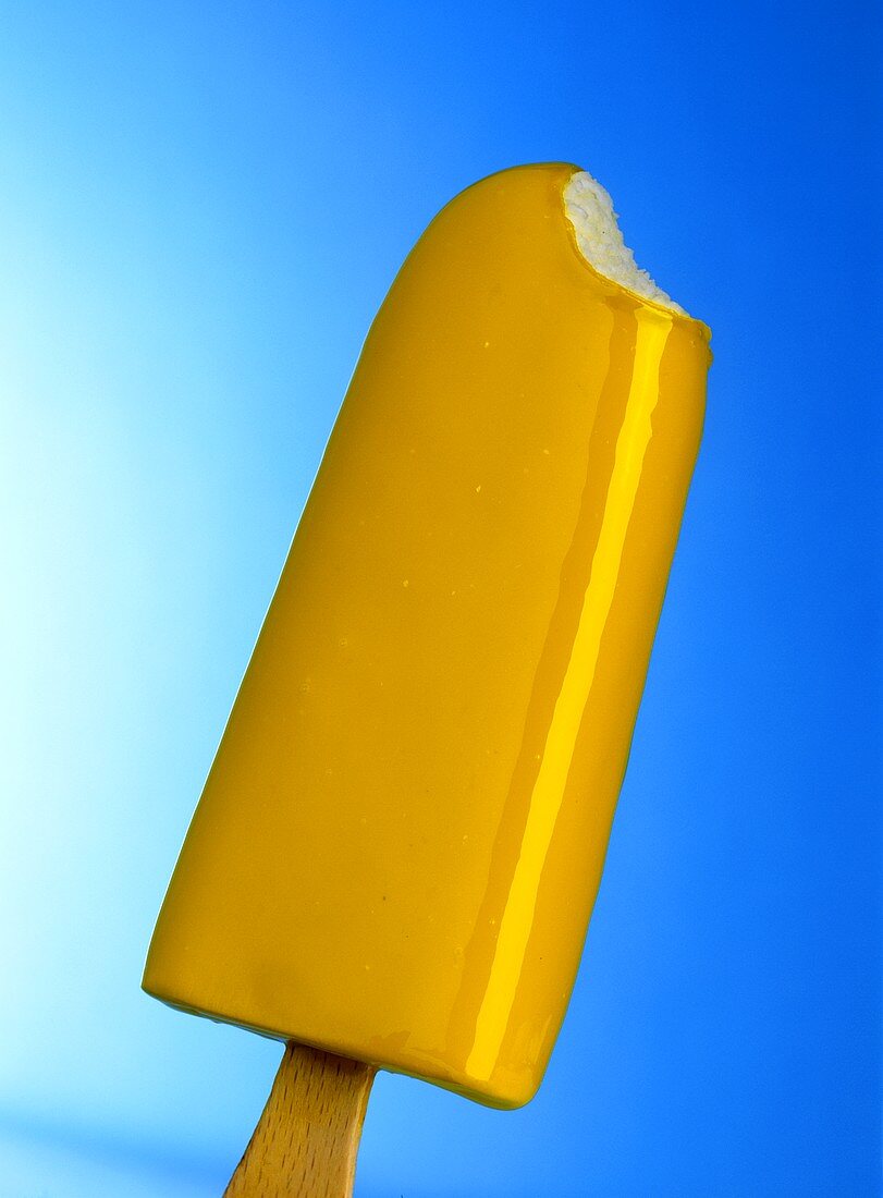 Vanilla ice cream with yellow fruit glaze on stick