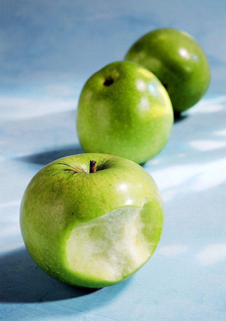 Granny Smith apples, one with a bite taken
