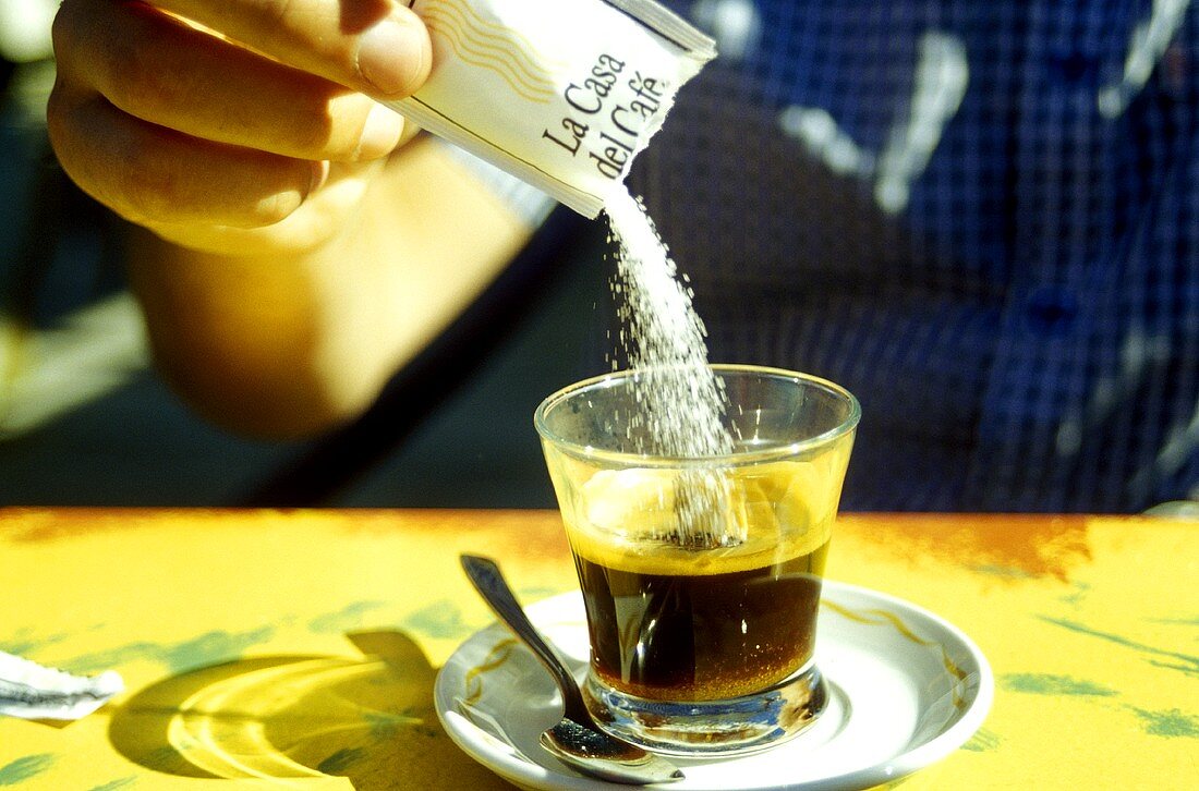 Zucker in Kaffee schütten